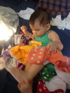 baby helping sort laundered cloth diapers